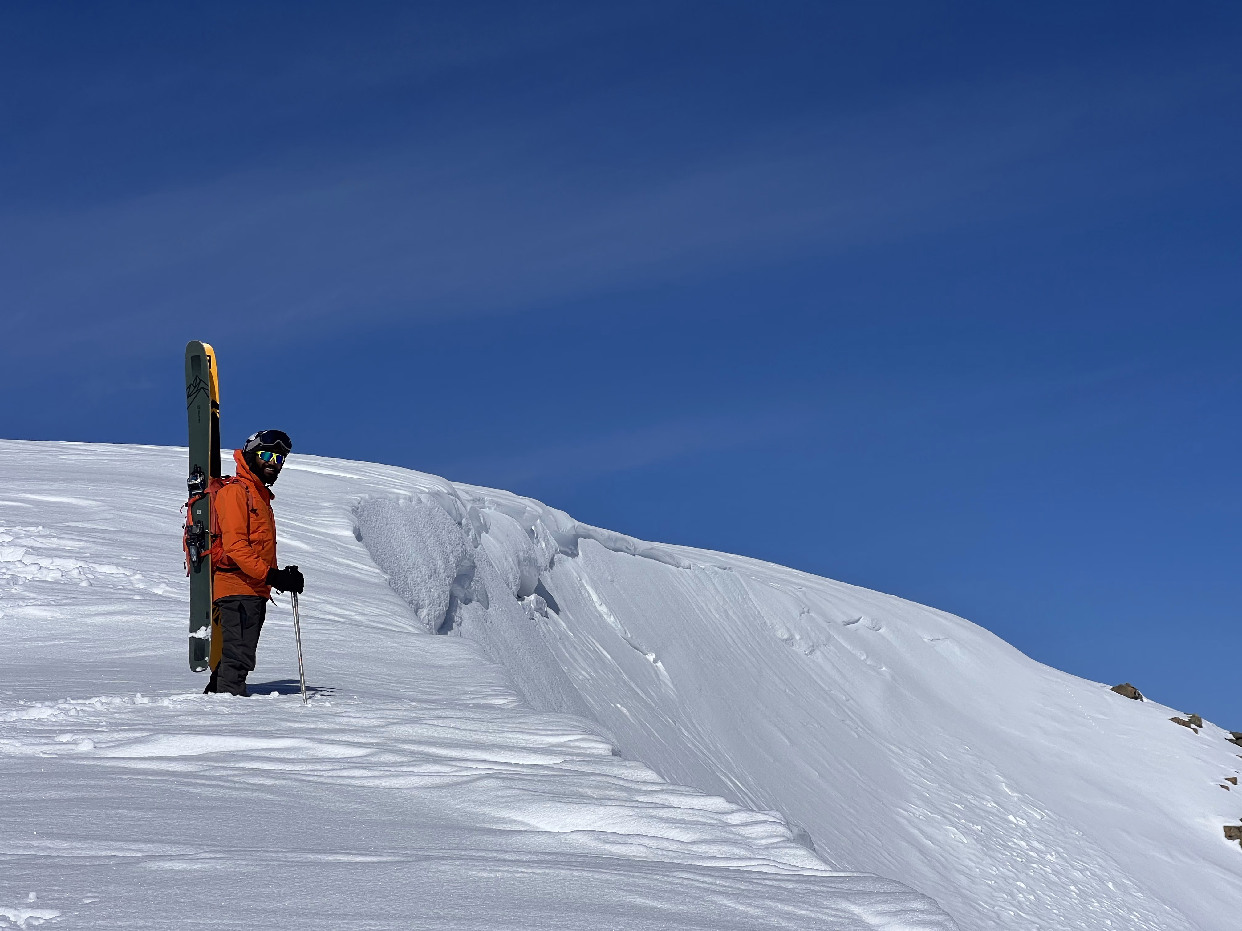 Skier picking a line through open powder below the treeline