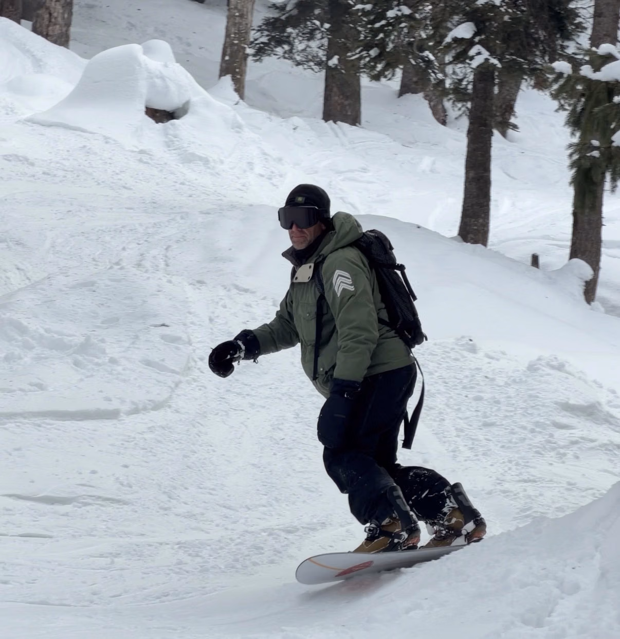 Freeride snowboarder descending an open powder face on Apharwat